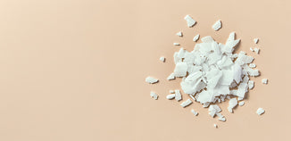 White sodium hydroxide flakes piled on a beige background.
